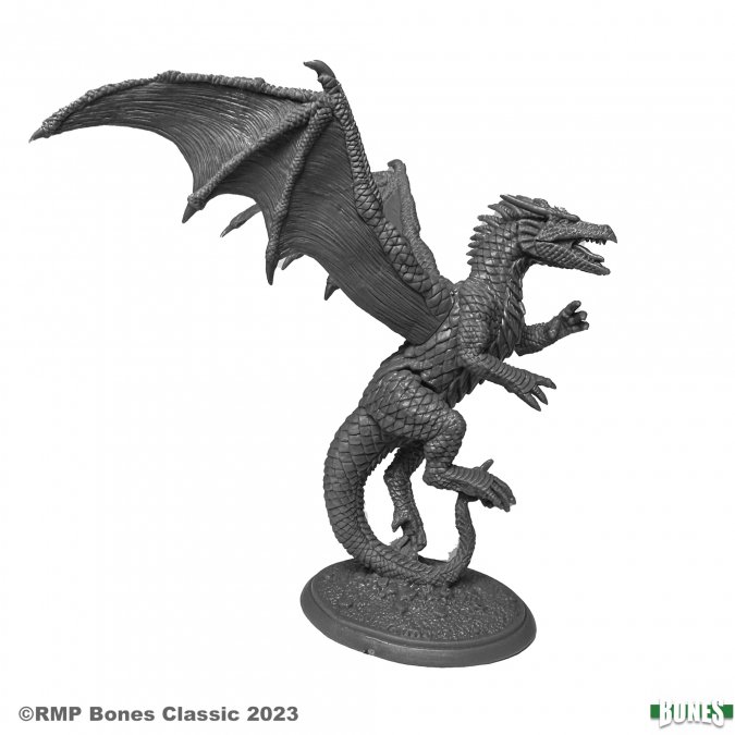 A detailed gray plastic miniature of a dragon in a dynamic, mid-flight pose. The dragon features large, outstretched wings with visible membrane texture, a long sinuous tail curling beneath it, and sharp claws extended as if ready to strike. Its body is covered in finely sculpted scales, and its mouth is open in a fierce roar, revealing pointed teeth. The figure is mounted on a round textured base and remains unpainted.